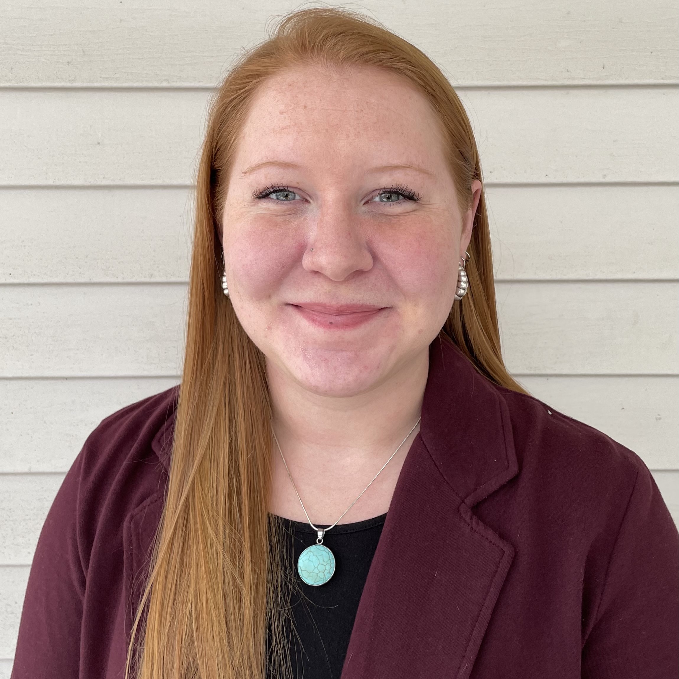 Sydney's headshot in front of a white wall.