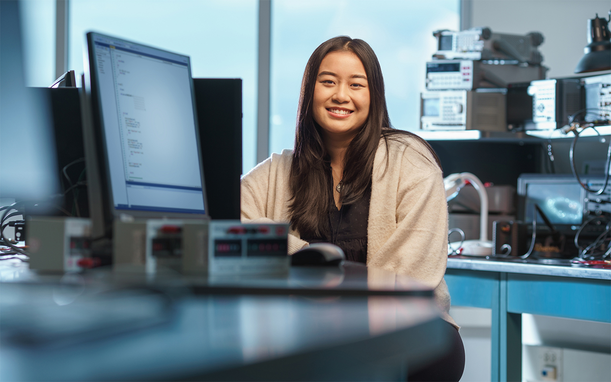 Student smiling by a computer