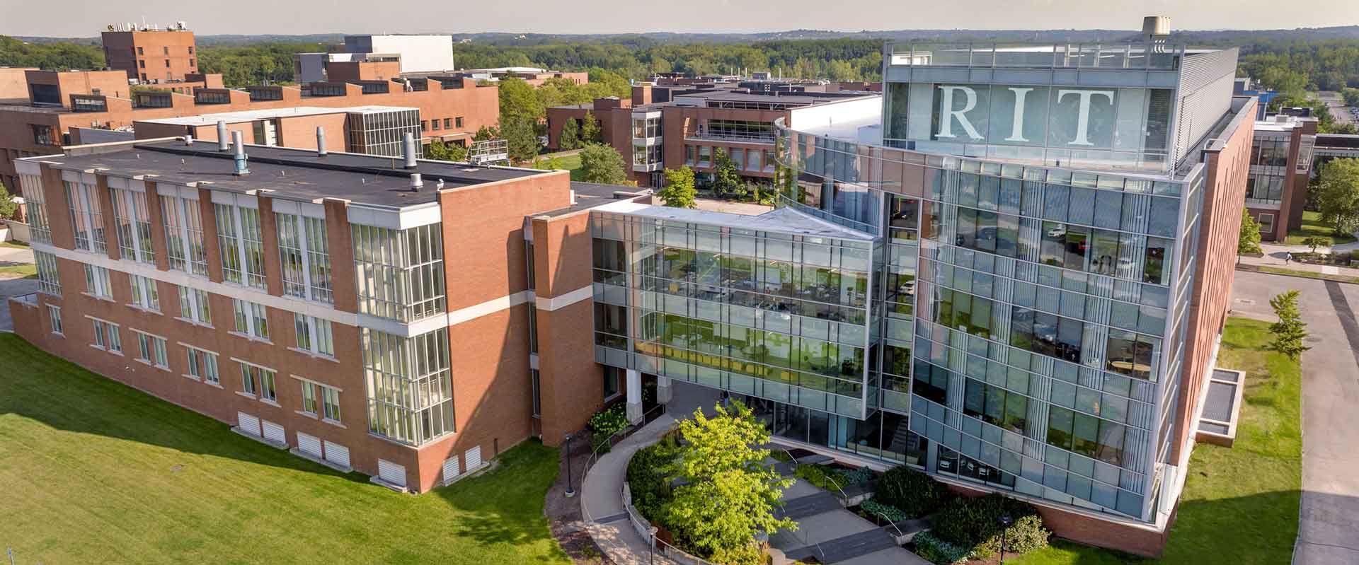 a drone view of a large brick a glass building on the R I T campus