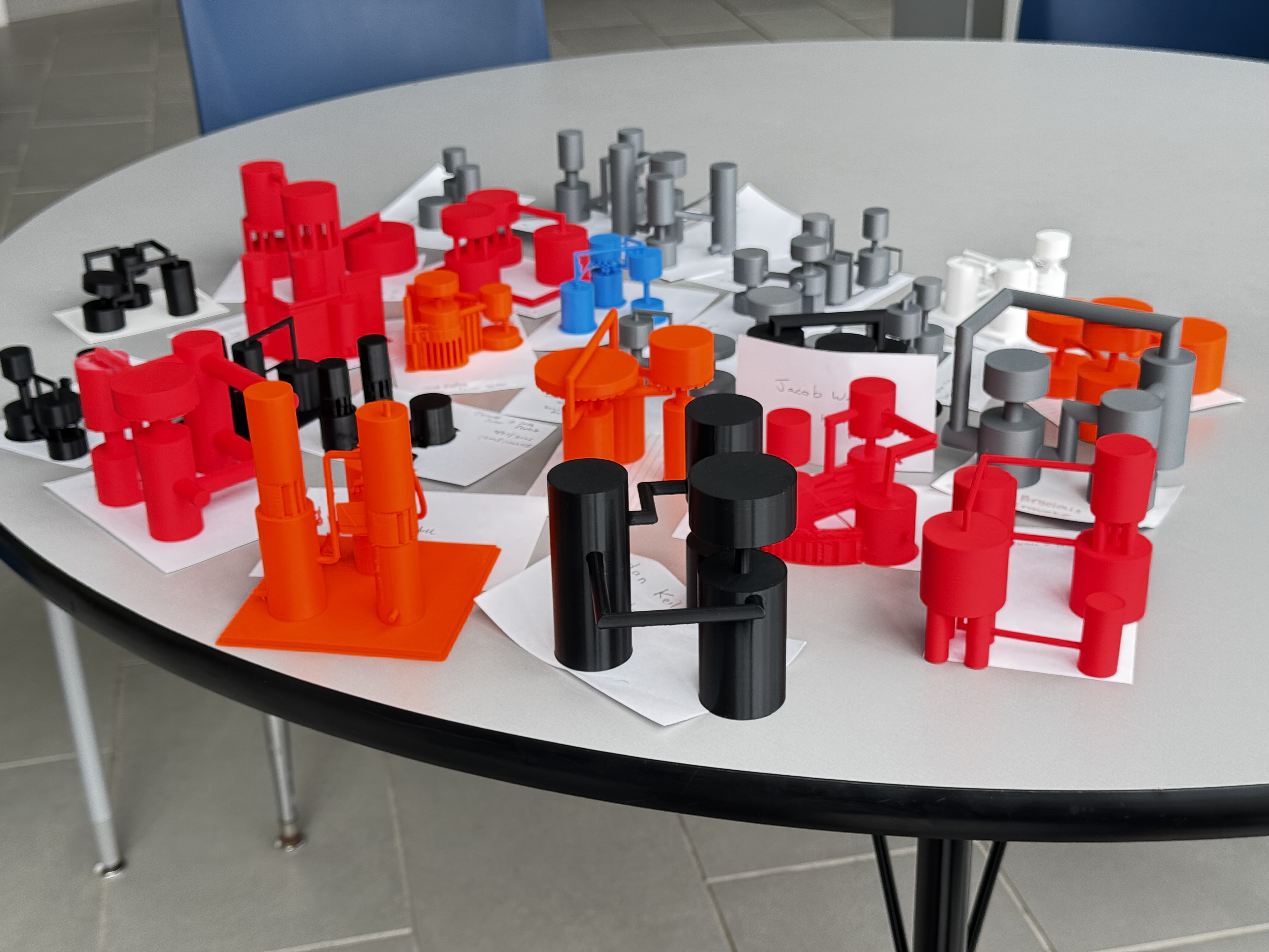 Image showing several 3D printed cylinders connected by pipes on a white table.