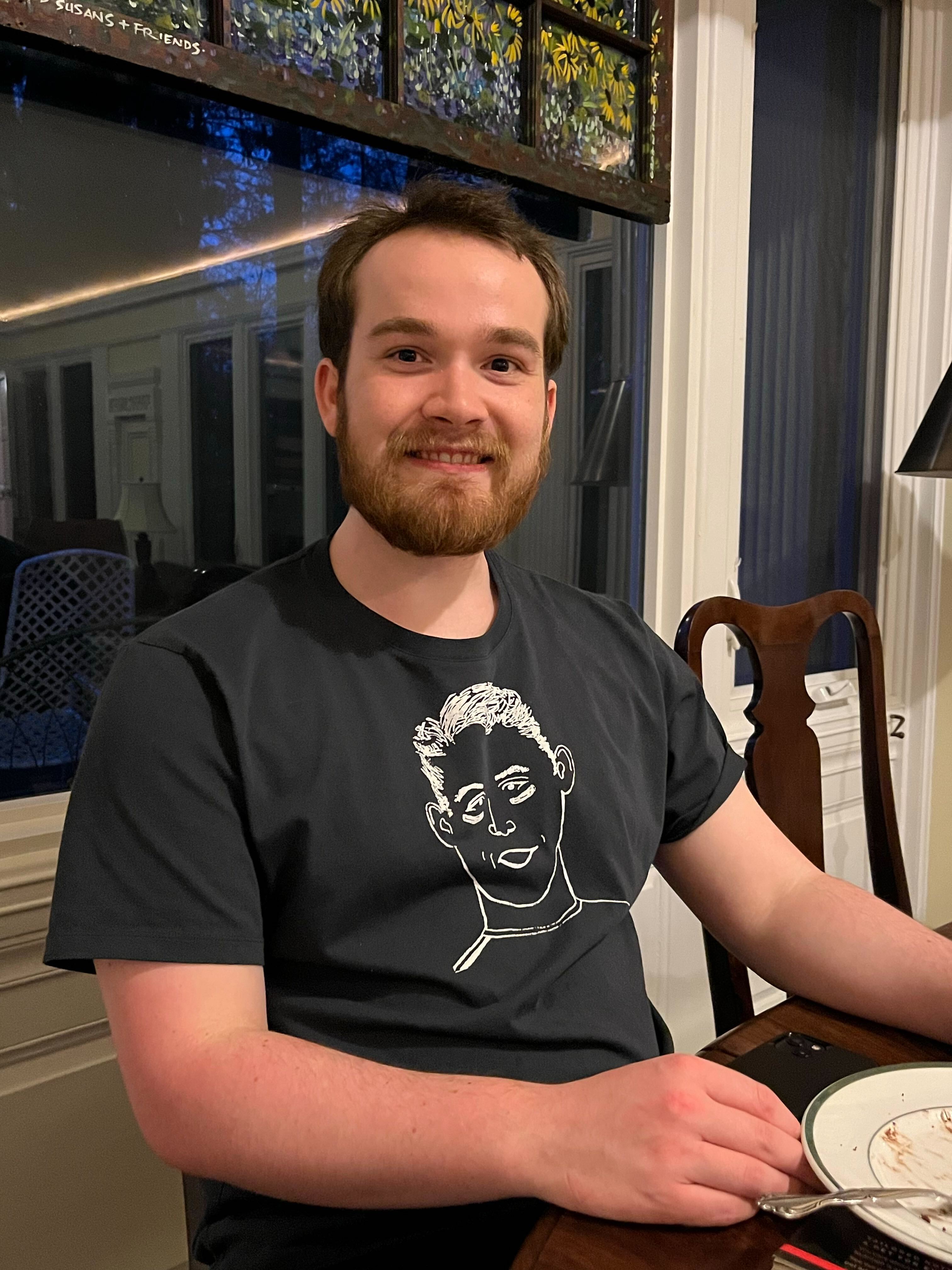 Connor wearing a black T-shirt sitting at a dinner table.