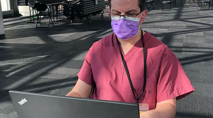 Dr. Christopher Tanski in purple scrubs and a medical mask
