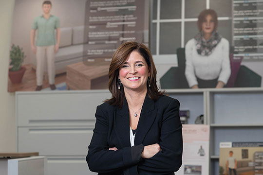professor posing in front of two posters featuring health care worker avatars.