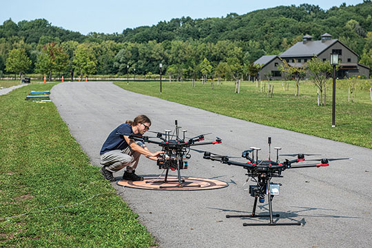 A drone pilot working on a drone that is on the ground.
