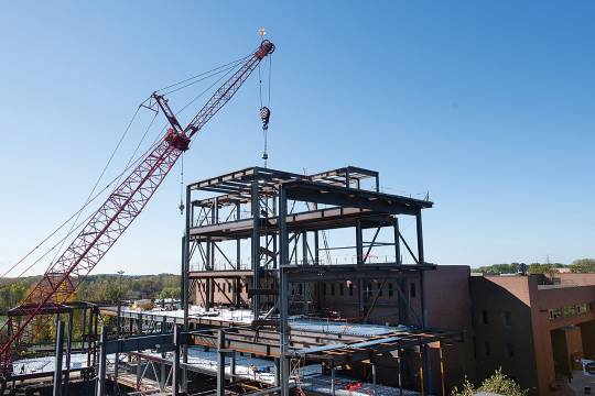 crane putting support beams into place on a building construction project.