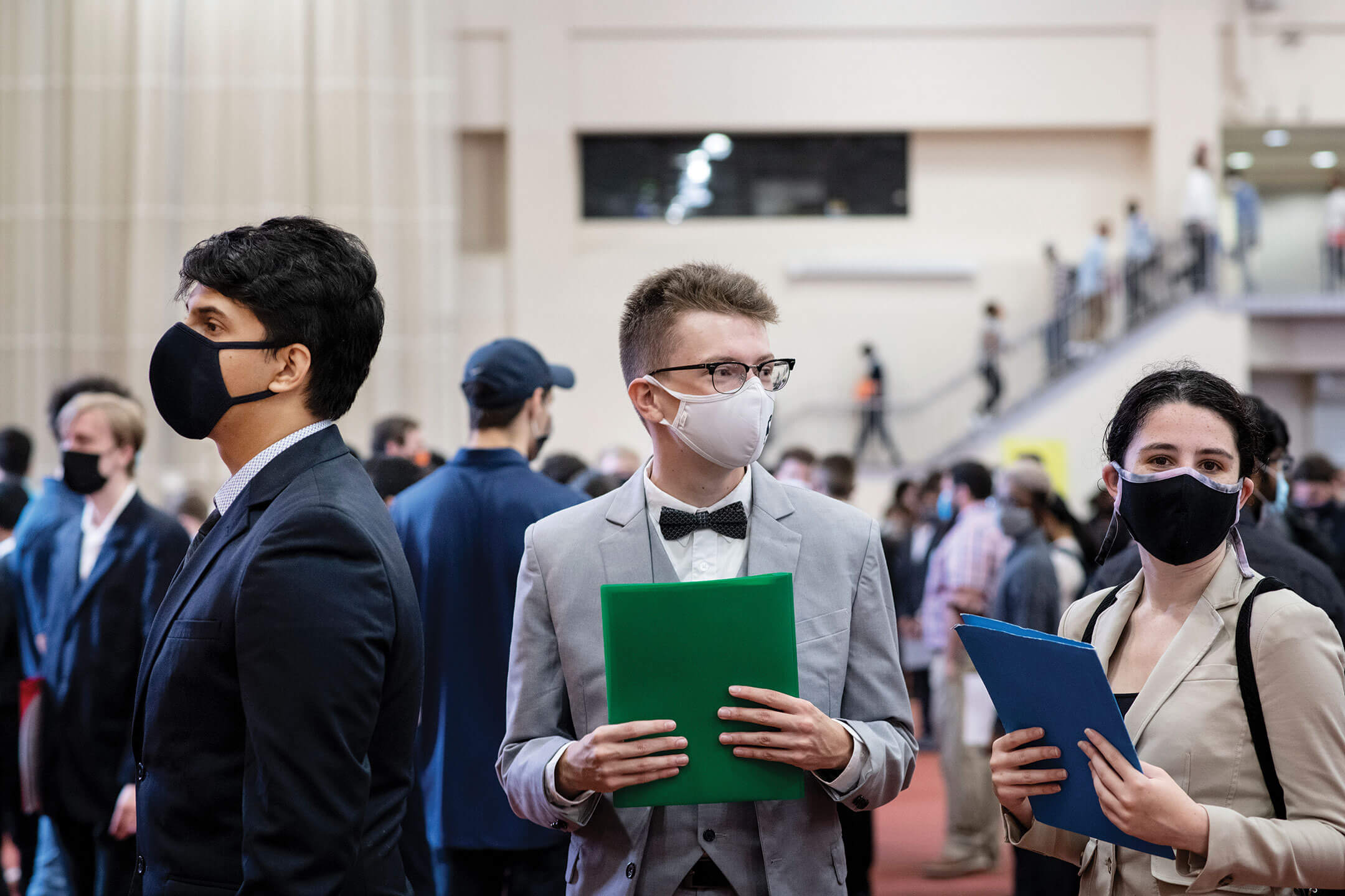 Two students working in a lab, one polishing copper pipes and the other has their hands in a hood.