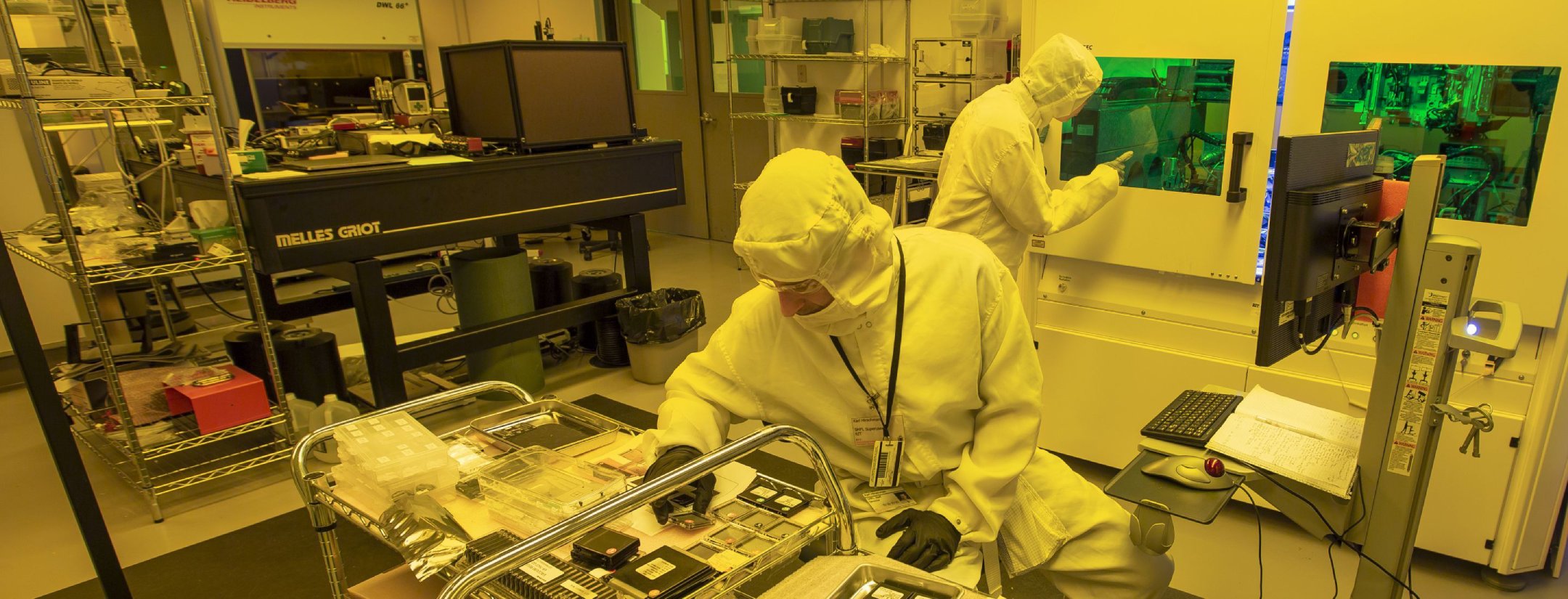A group of people outside on a sidewalk bending and kneeling down using chalk on the ground