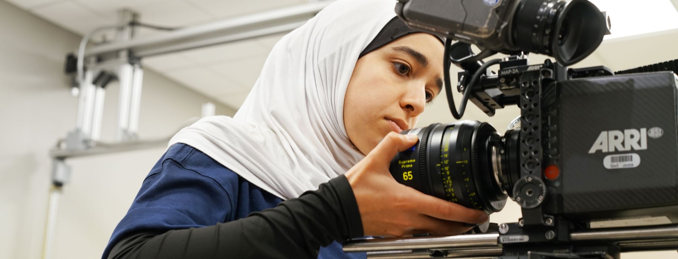 Two students working in a lab, one polishing copper pipes and the other has their hands in a hood.