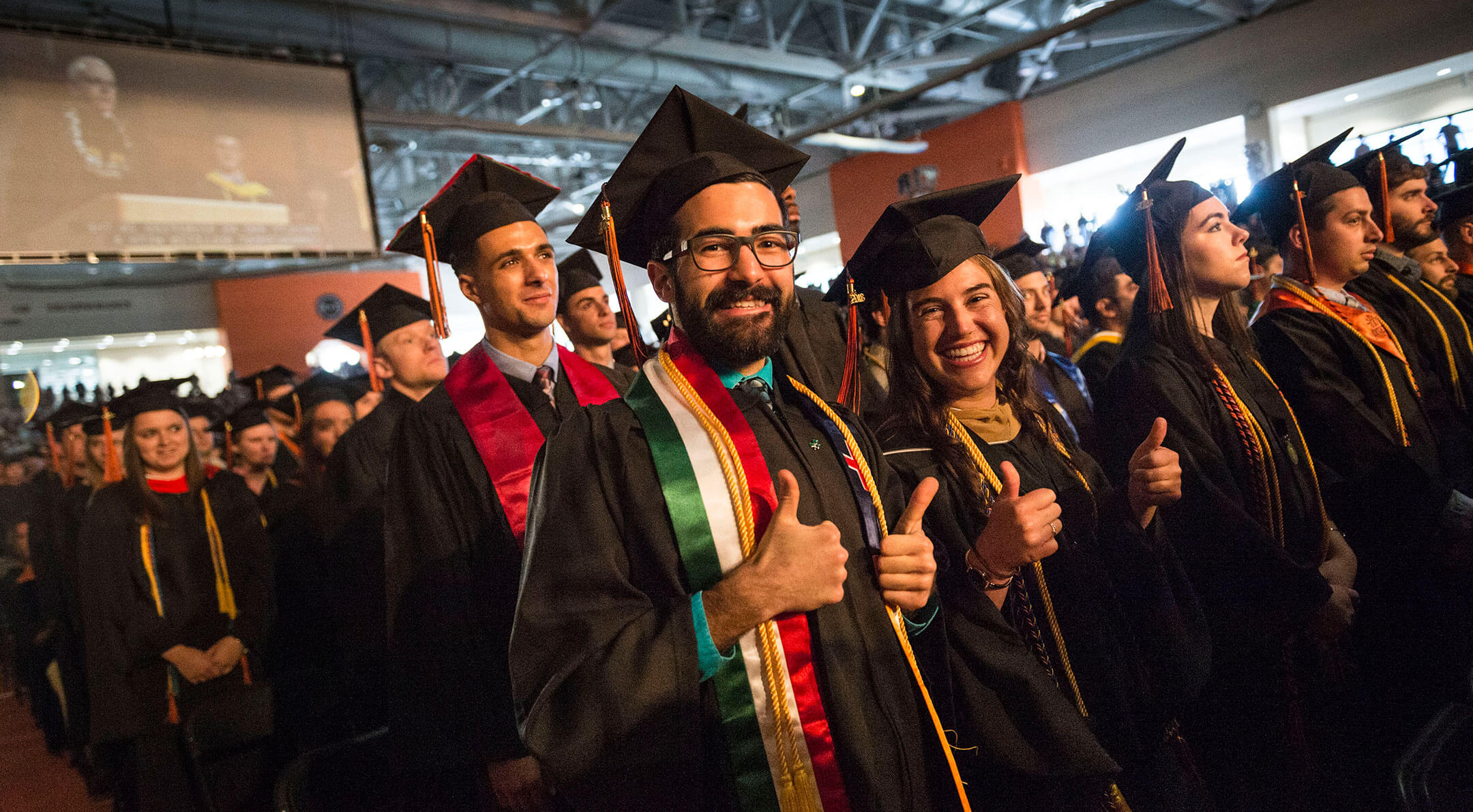 Graduates wearing their caps and gowns smiling at a graduation ceremony