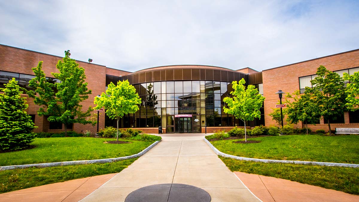 exterior view of a brick and glass building with a rounded central atrium and two wings on either side.