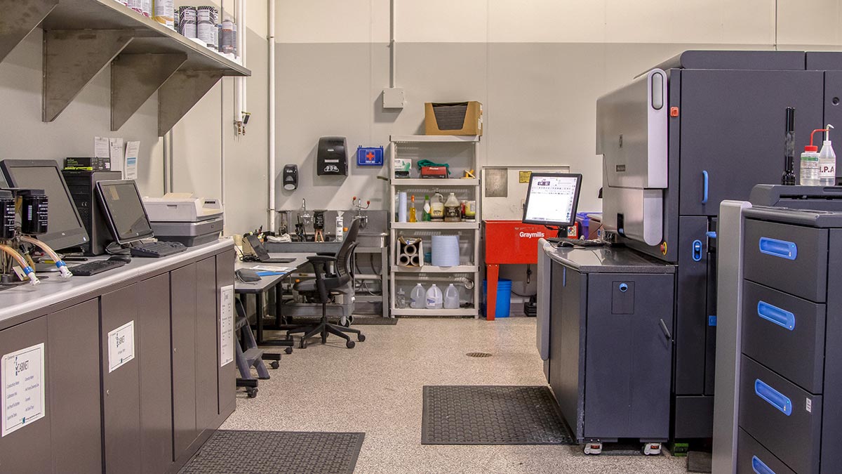 a lab setting with large equipment, computers, and shelves of various ingredients and paints.
