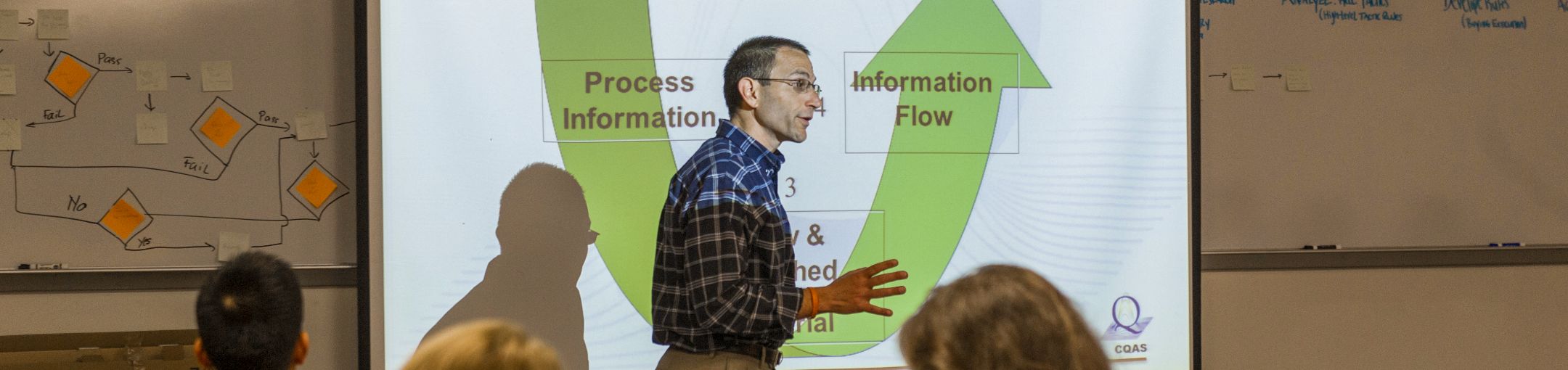 a professor lecturing in front of a projected info graph