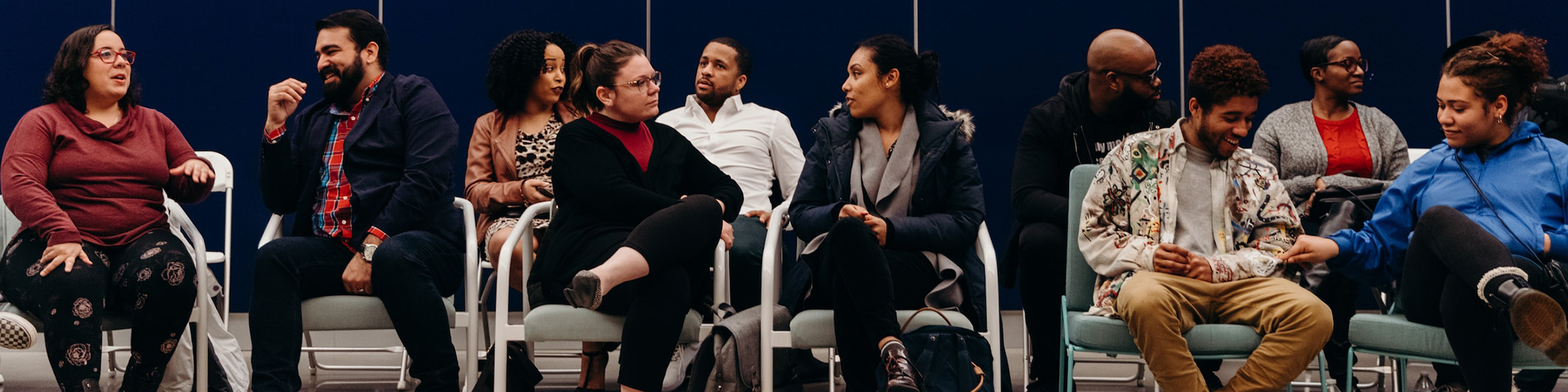 Diverse group of people sitting in chairs having conversations