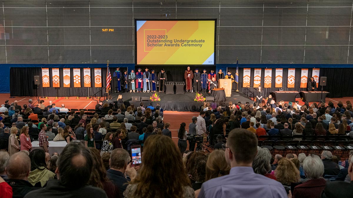 A wide shot of the Outstanding Undergraduate Scholar Awards Ceremony with faculty on stage and an audience seated.