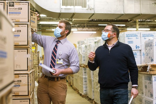 student and professor looking at stacks of boxes.