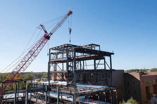 crane putting support beams into place on a building construction project.
