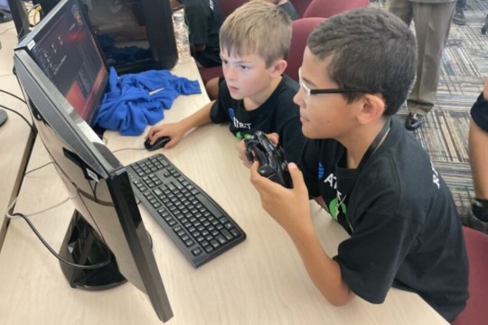 Two elementary school kids play on computer. 