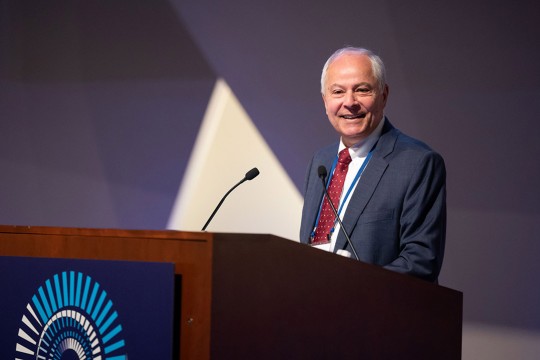 Nabil Nasr is pictured standing at a podium giving a speech.