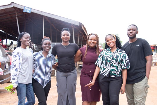 a group of 6 people stand in a village in a remote area.