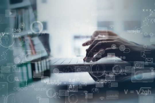 Hands type on a laptop keyboard.