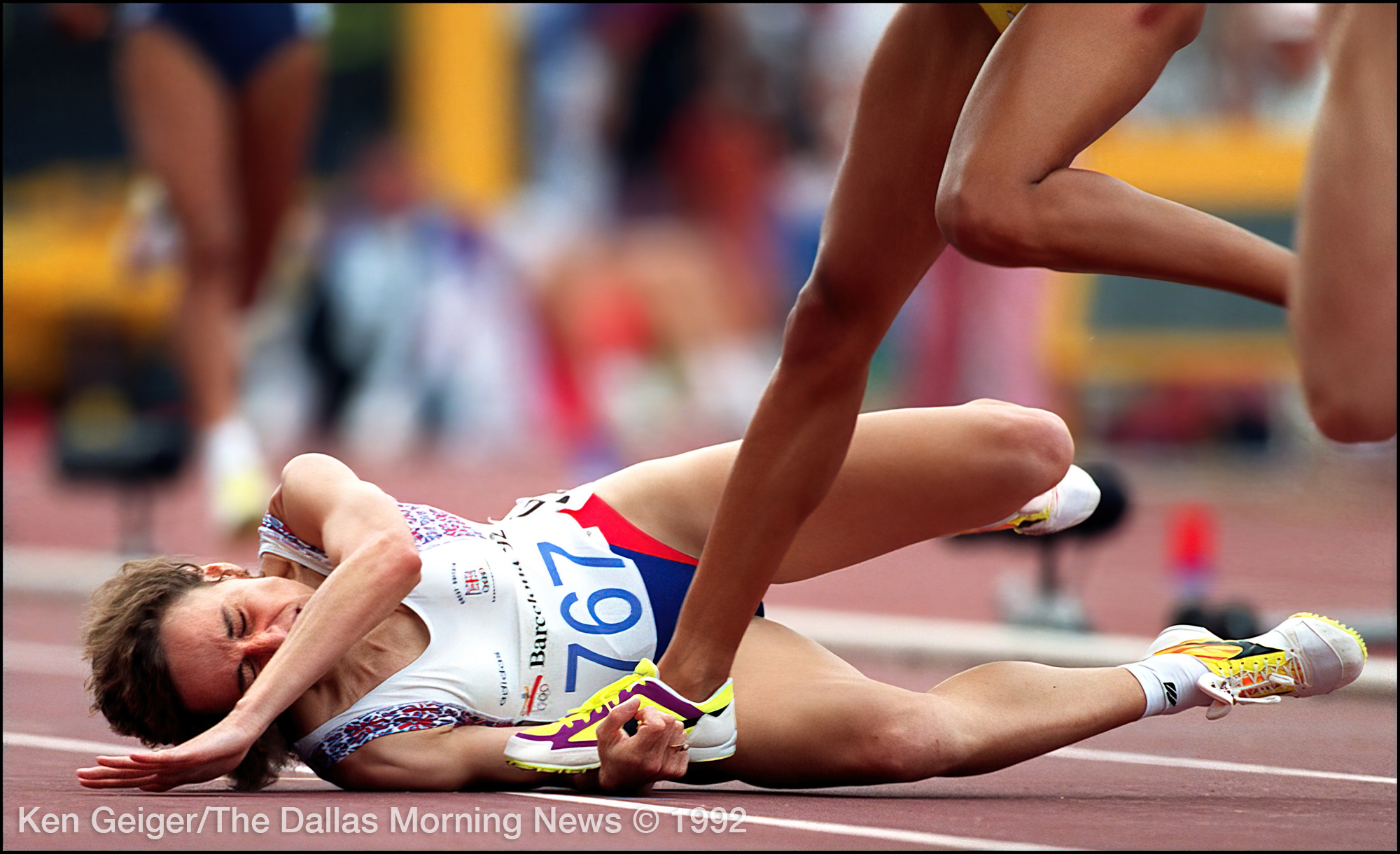 a track runner who has fallen down getting stepped on.