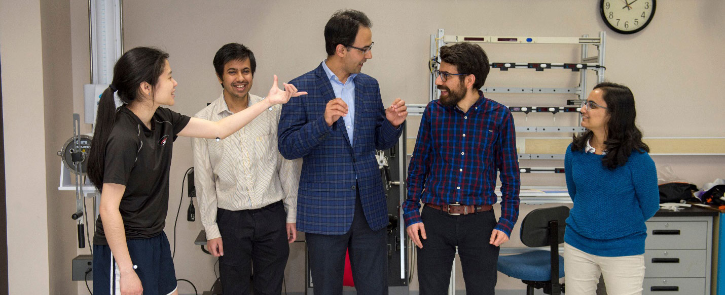 a group of five people talks and laughs together in a lab.