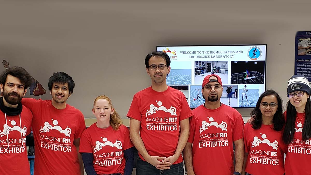 a group of people wearing red Imagine R I T T-shirts poses in a lab.