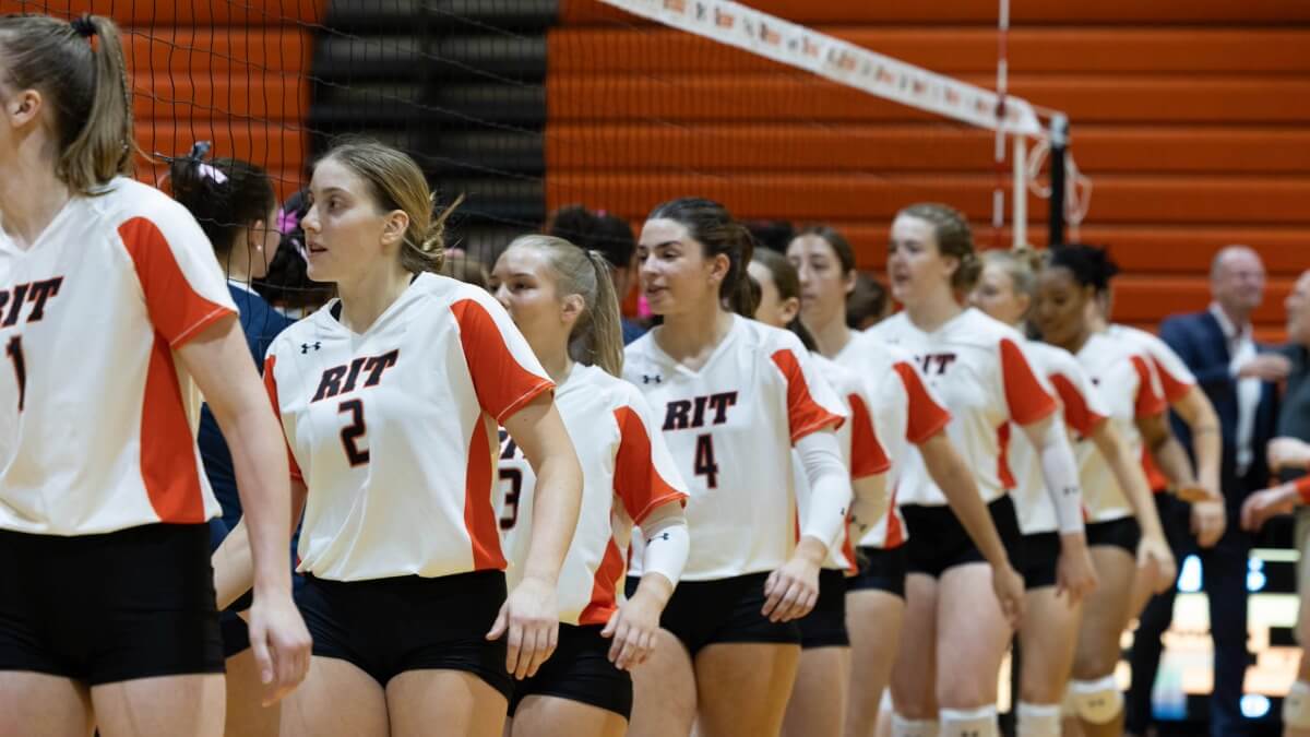 A group of girls playing volleyball, lining up at the net