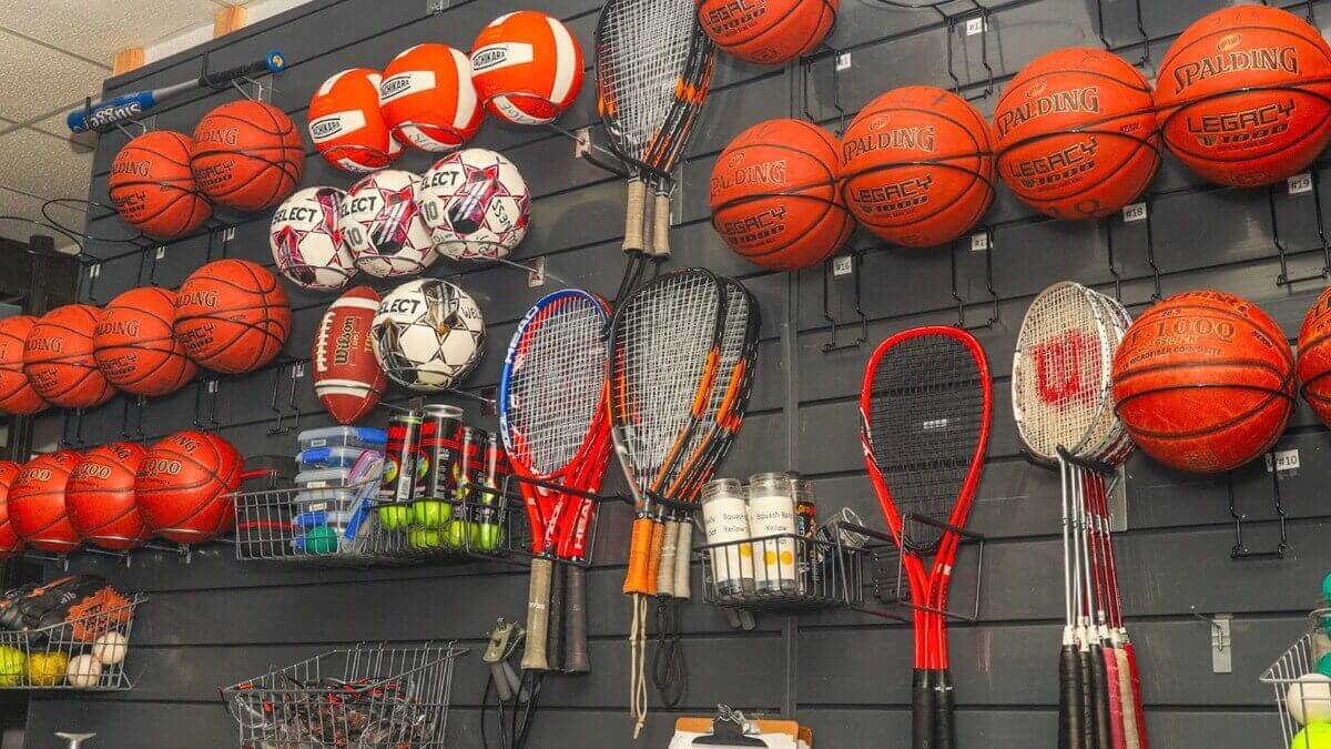 fully stocked wall of equipment at the Cage for students to rent, basketballs, tennis racquets and more