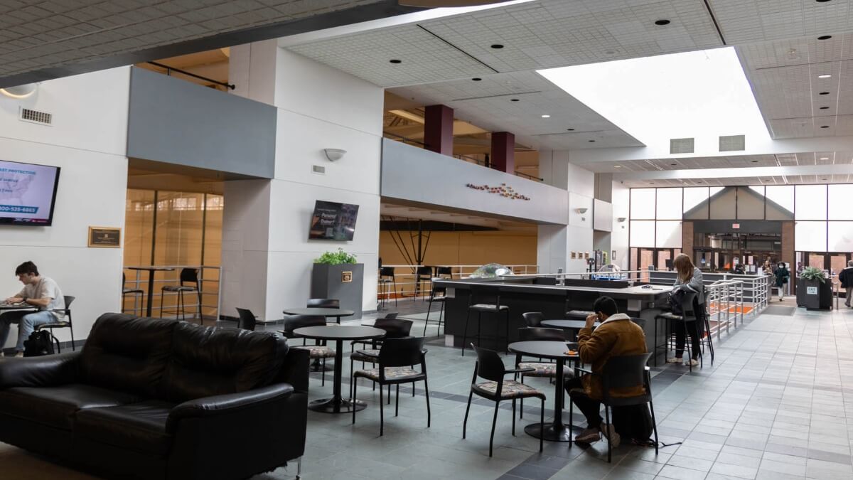 the SLC upper lobby with students sitting at various tables .