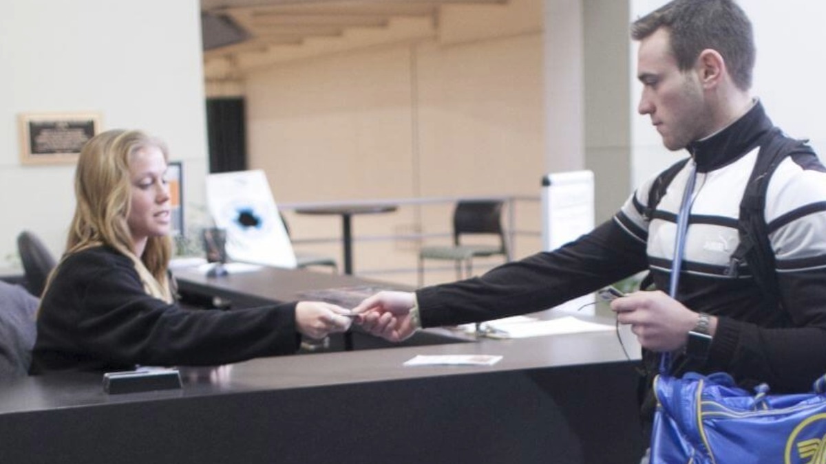 A student worker checking in another student to use the indoor recreation facilities.