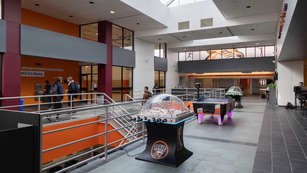 the Student Life Center open hangout area, students walking in the background and various games and seating options
