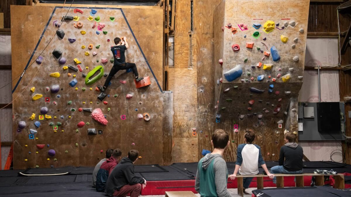 Wide shot of students climbing on the rock climbing wall at the Red Barn facility 