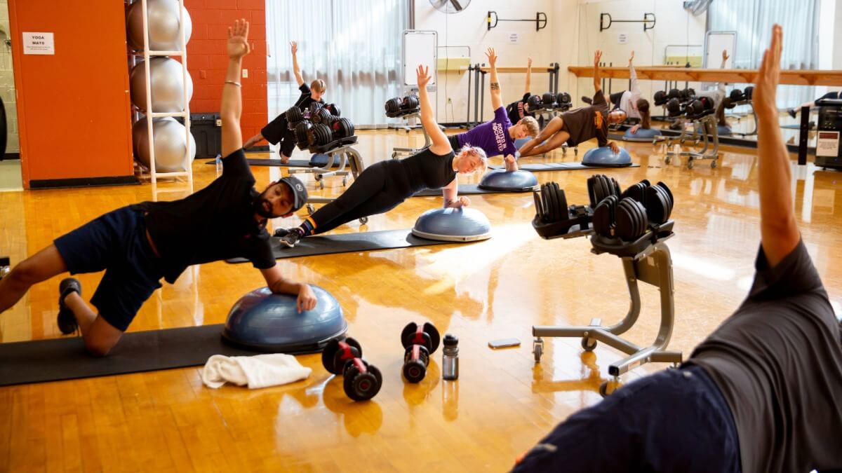 A group of students balancing in side plank position during a wellness education course