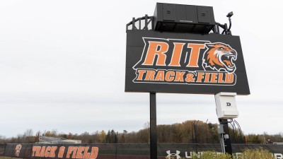 Large sign with text "RIT Track & Field" in orange letters with RIT Tiger head