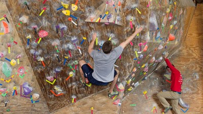 Two people hanging off of an indoor rock wall