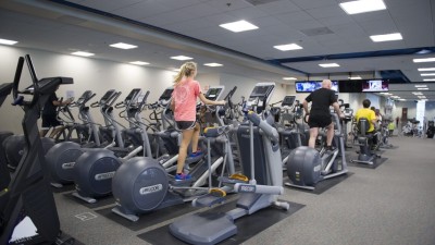Two rows of ellipticals in the Wiedman Fitness Center with people using the exercise machines