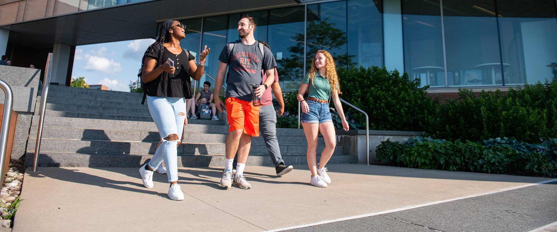 four students walking near the RIT Student Hall for Exploration and Development.
