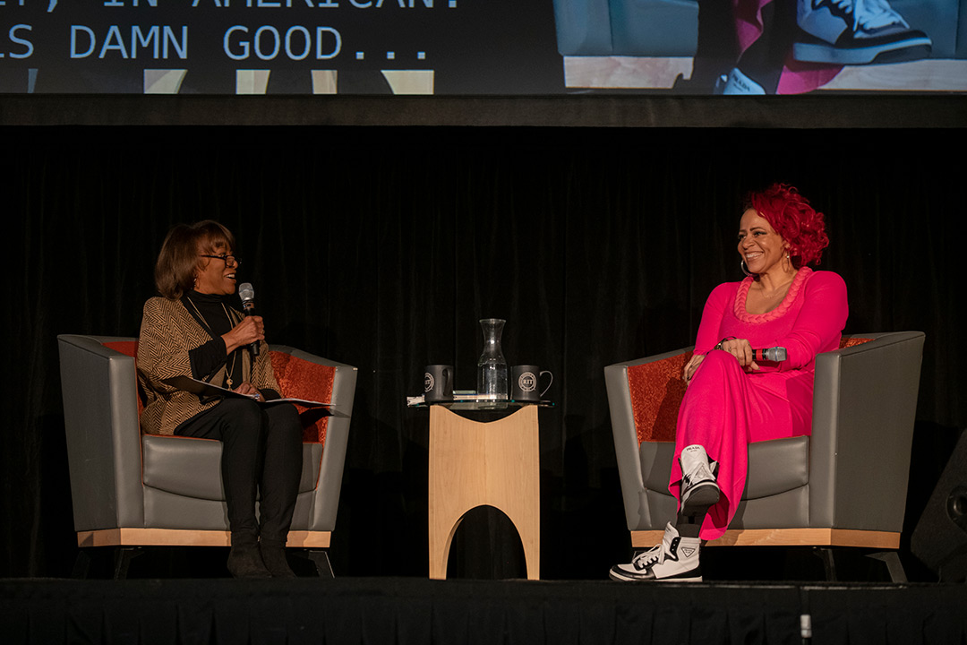two people sitting in arm chairs on a stage.