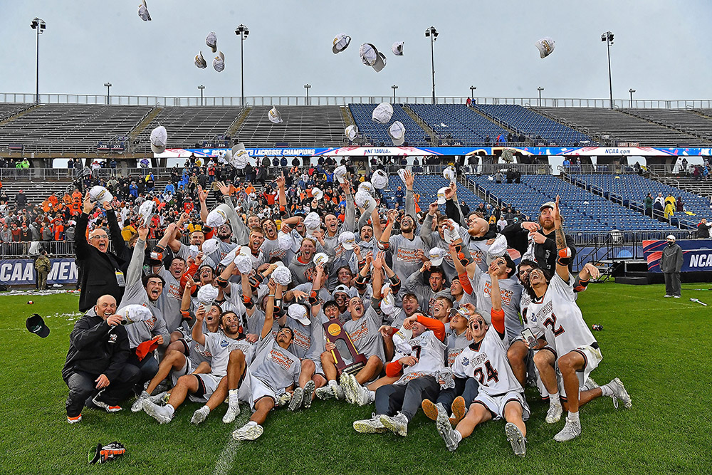 men's lacrosse team celebrating by throwing their hats into the air.