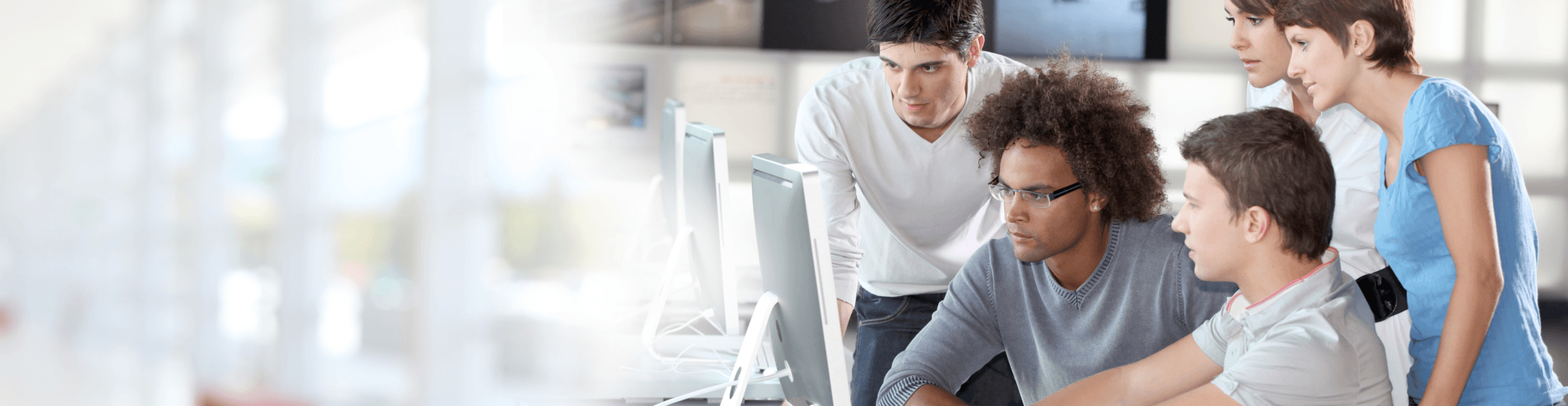 group of diverse people looking at a computer screen.