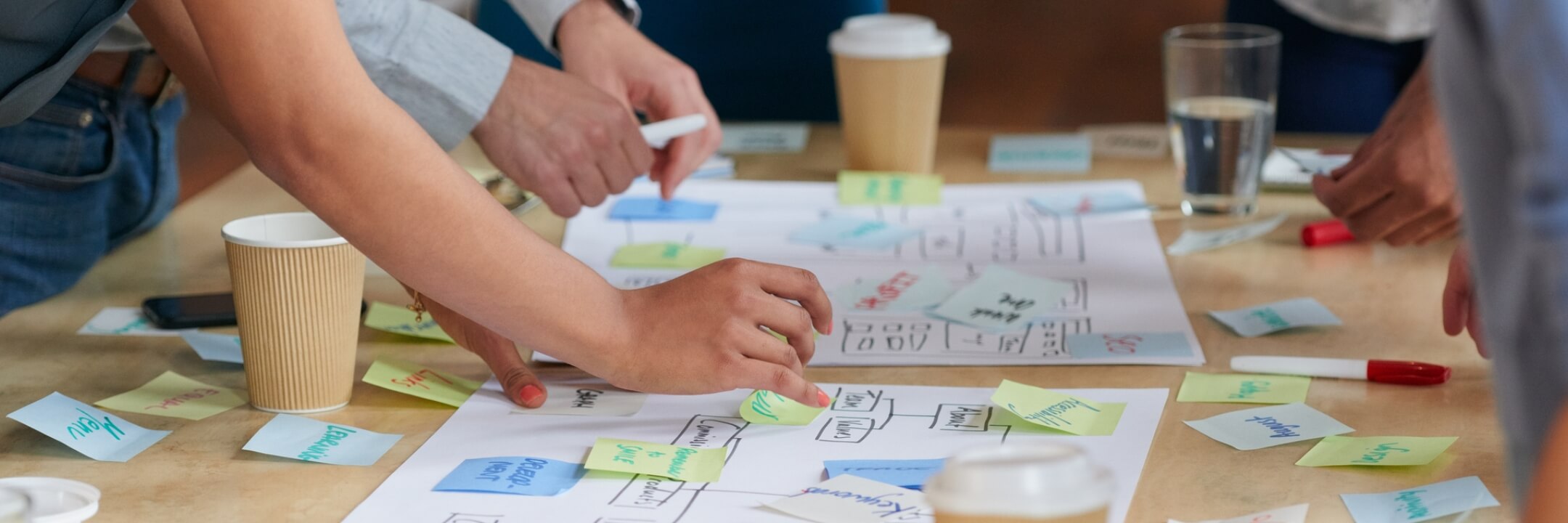 A close up of people sticking sticky notes to decision trees or flow charts.