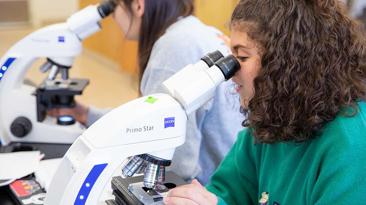 female student looking into a microscope