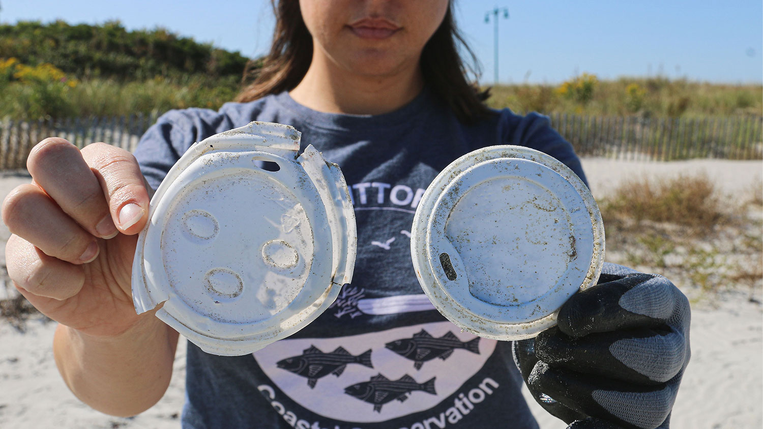 woman holding up two plastic coffee cup lids