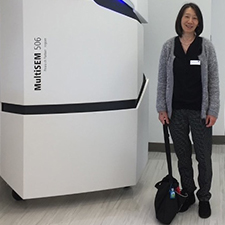 Dr. Ru-ching Hsia standing next to a MultiSEM 506 which is a scanning electron microscope. 