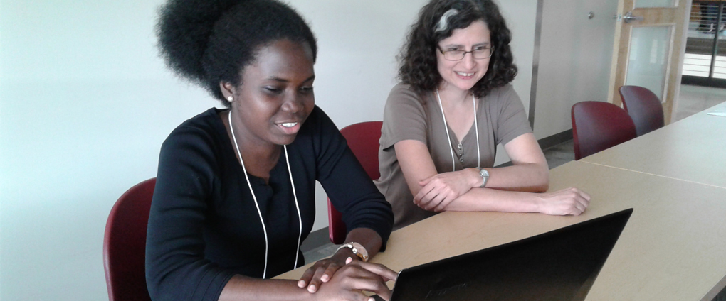 student working on laptop with professor