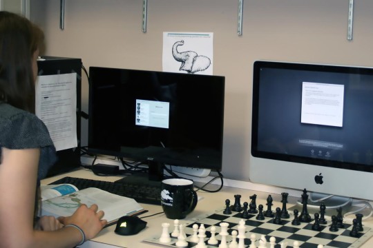 student using computer while reading a book.