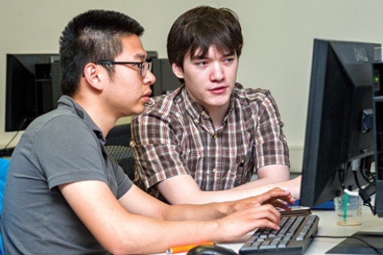 two people working on a computer.