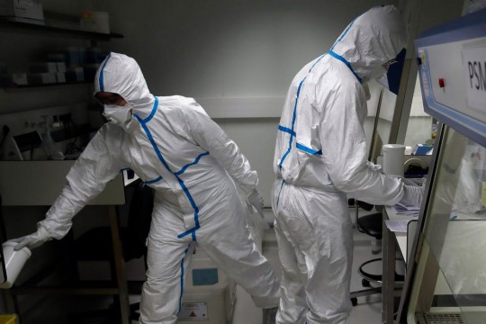two researchers wearing clean suits and face masks.