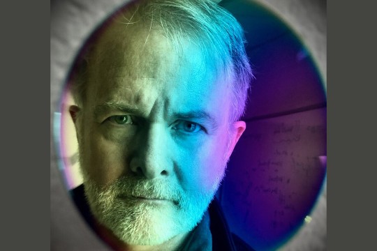 professor's face pictured in a reflection from a thin optical film.